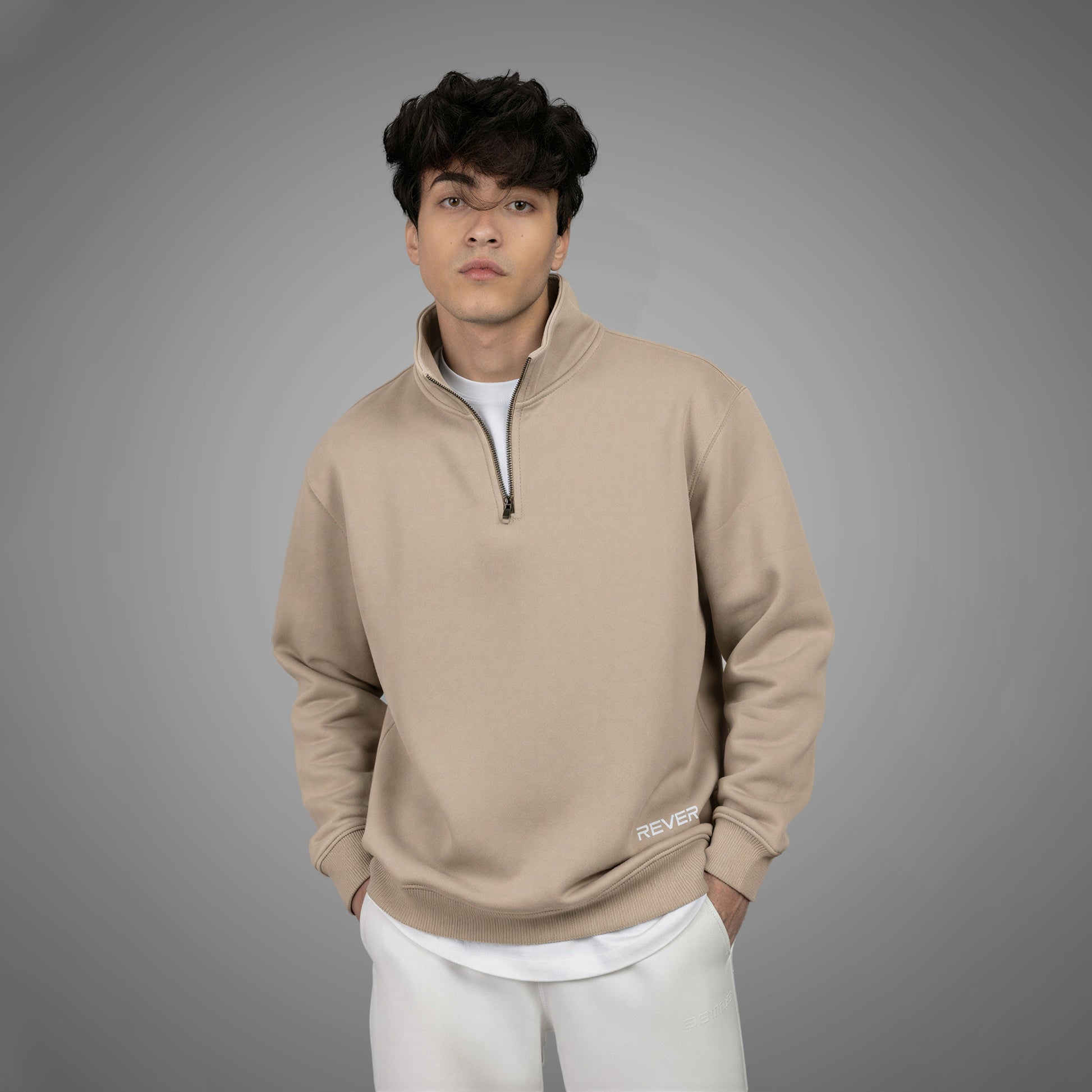 Man wearing a beige pullover with a zipper on a gray background