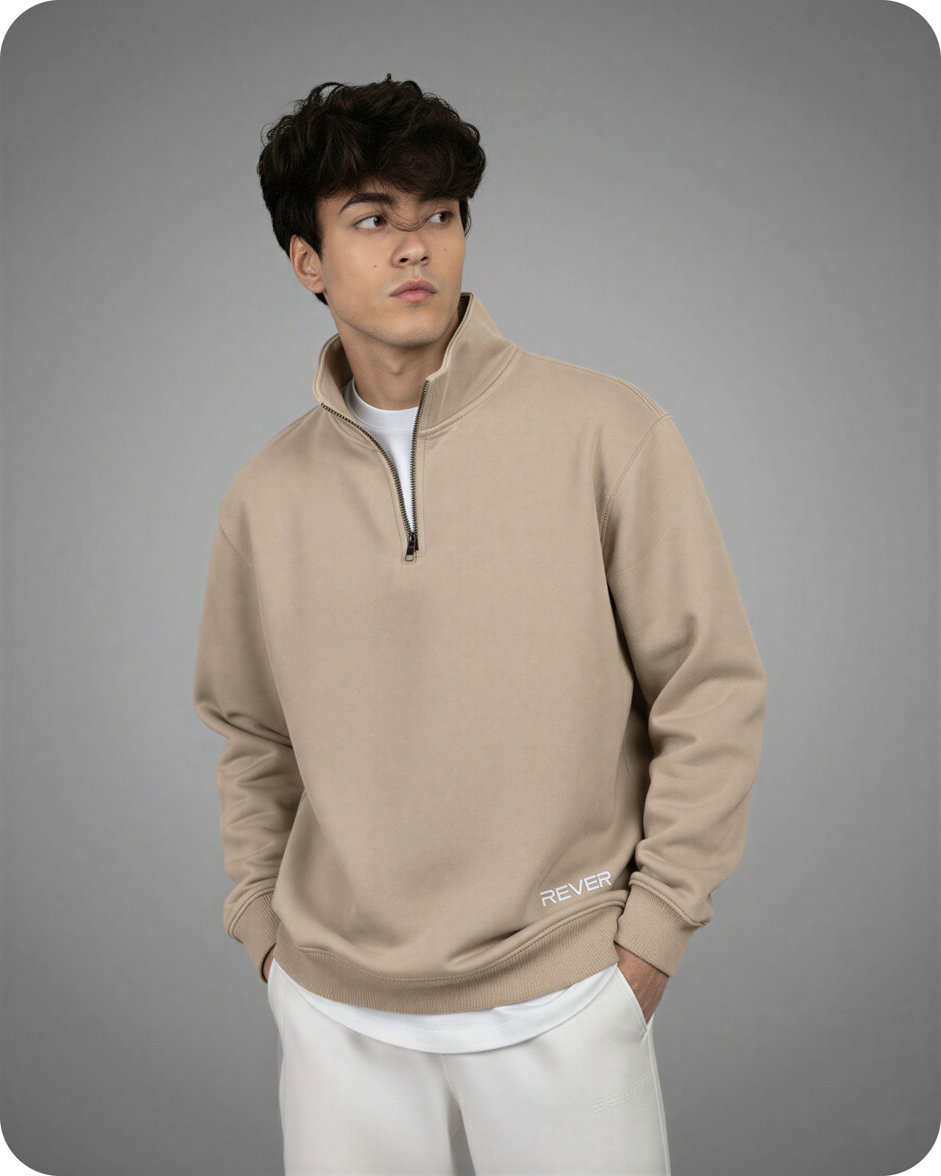 Man wearing a beige pullover with a logo on a gray background