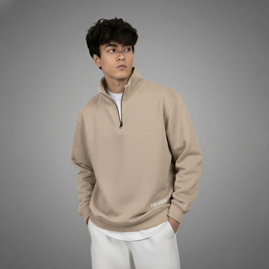 Man wearing a beige pullover with a logo on a gray background