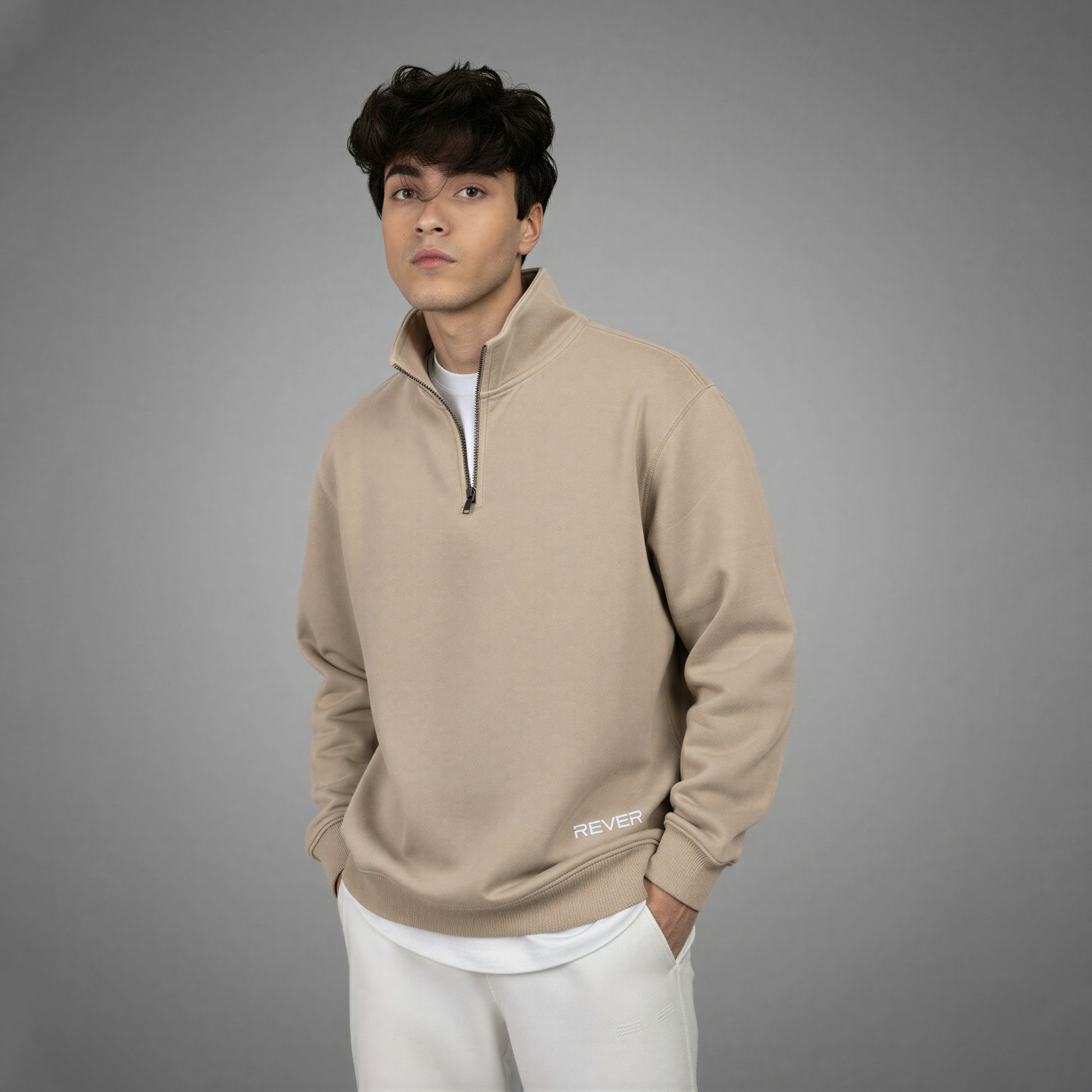 Man wearing a beige pullover with a logo on a gray background