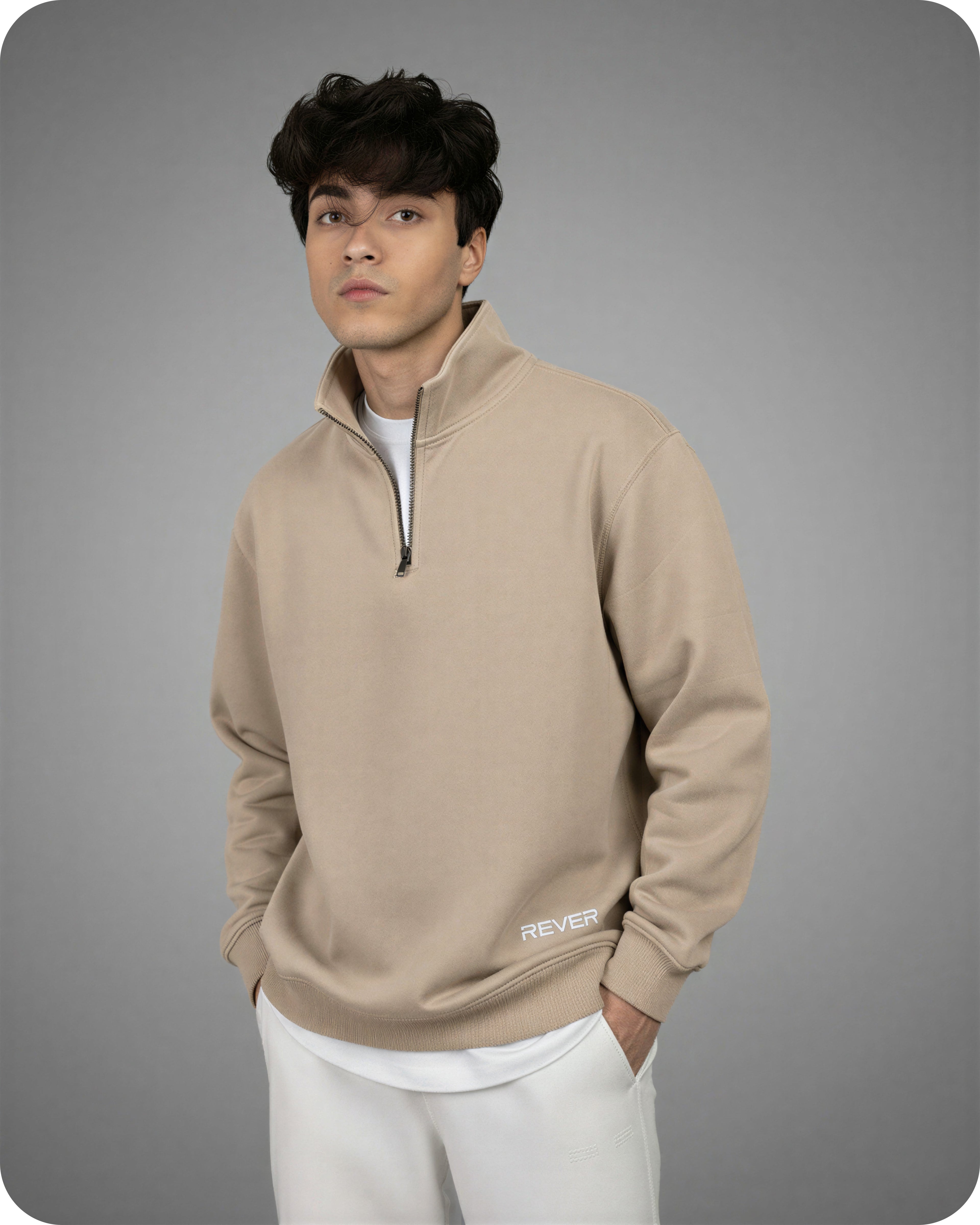 Man wearing a beige pullover with a logo on a gray background