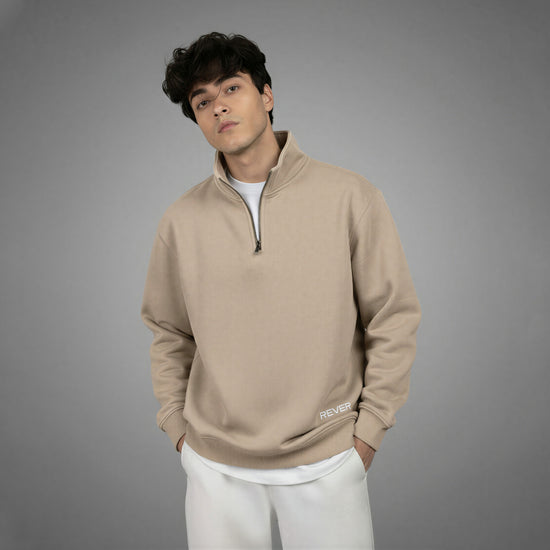 Man wearing a beige pullover with a zipper on a gray background