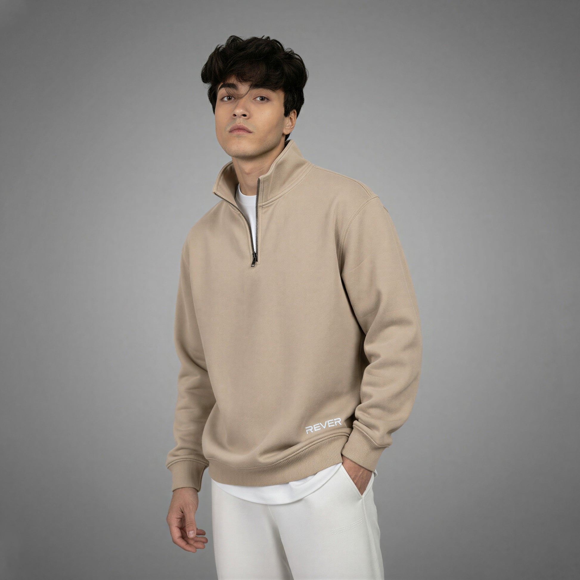 Man wearing a beige pullover with 'Rever' logo on a gray background