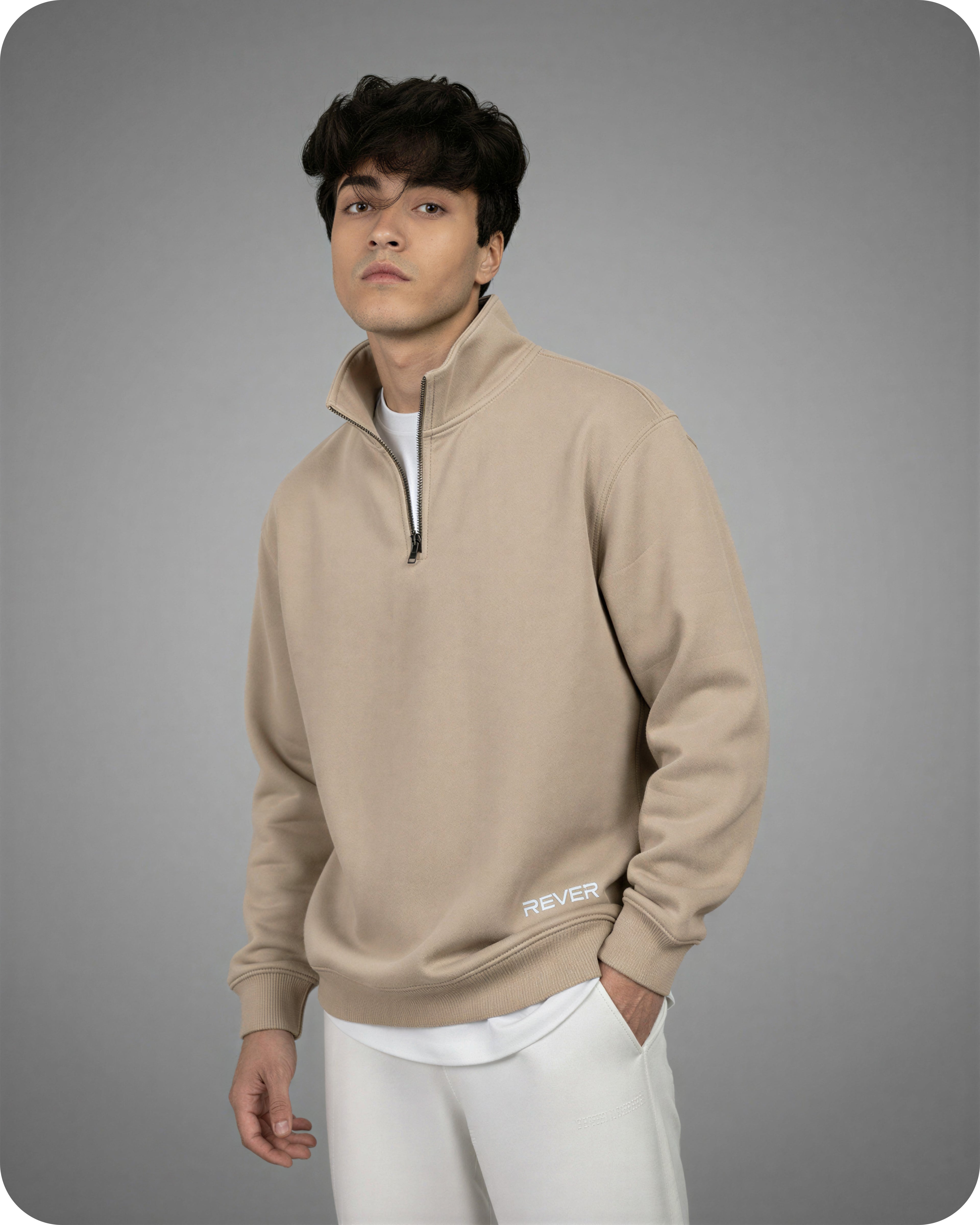 Man wearing a beige pullover with 'Rever' logo on a gray background