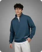 Person wearing a blue pullover with 'REVER' branding on a gray background