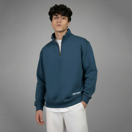 Man wearing a blue pullover with 'REVER' branding on a gray background
