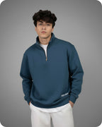 Person wearing a blue pullover with a zipper on a gray background