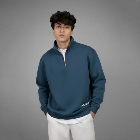 Person wearing a blue pullover with a zipper on a gray background