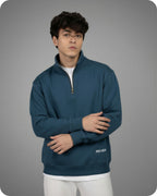 Person wearing a blue pullover with 'REVER' branding on a gray background