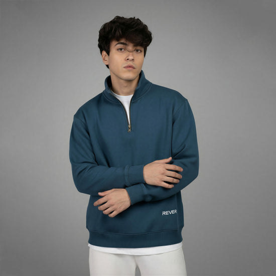 Person wearing a blue pullover with 'REVER' branding on a gray background