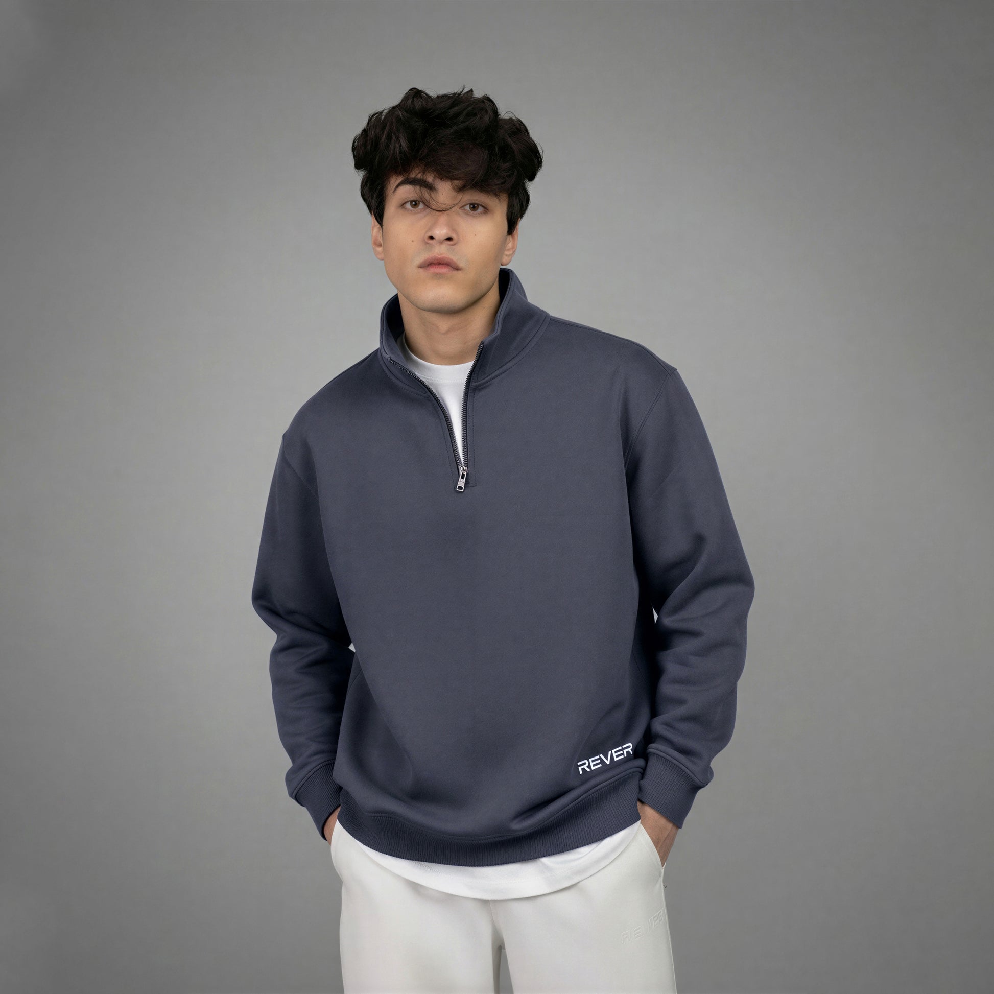 Person wearing a navy blue quarter-zip sweatshirt with 'Rever' branding on a gray background