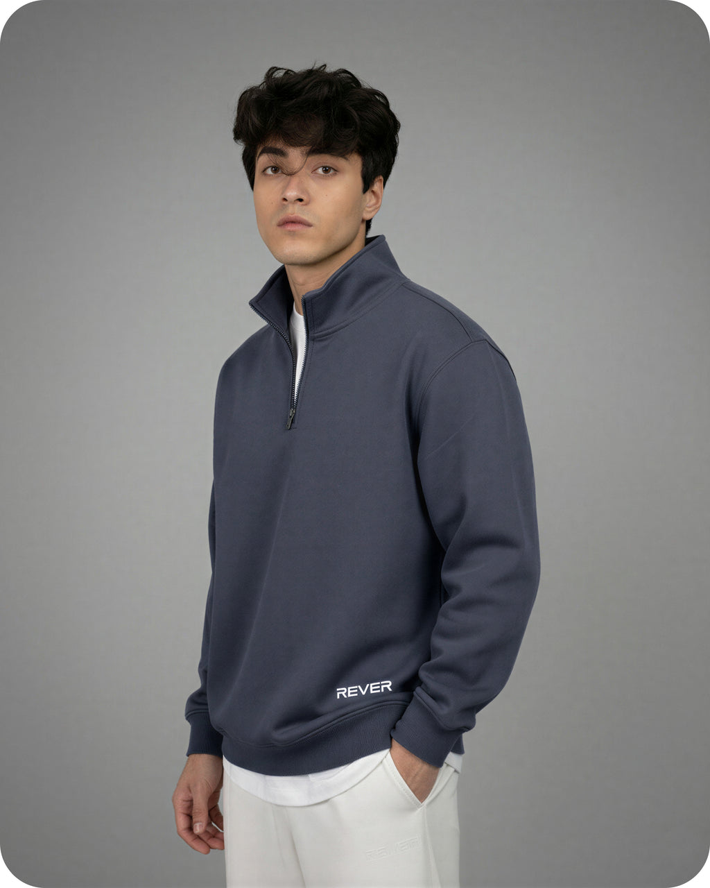 Man wearing a navy blue pullover with 'REVER' logo on a gray background