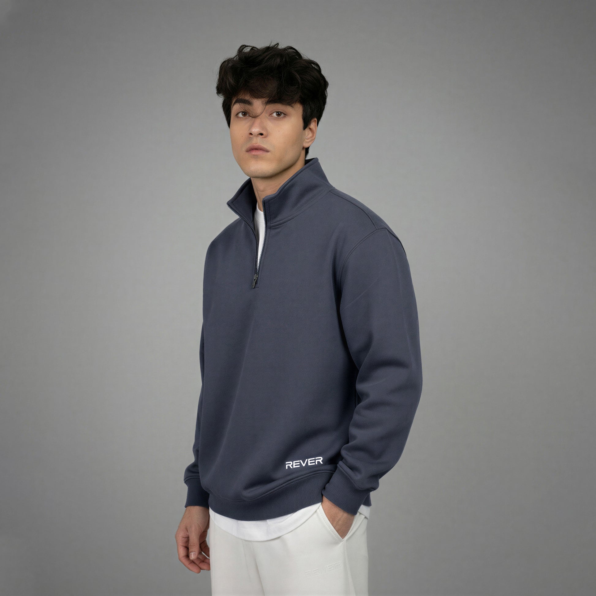 Man wearing a navy blue pullover with 'REVER' logo on a gray background