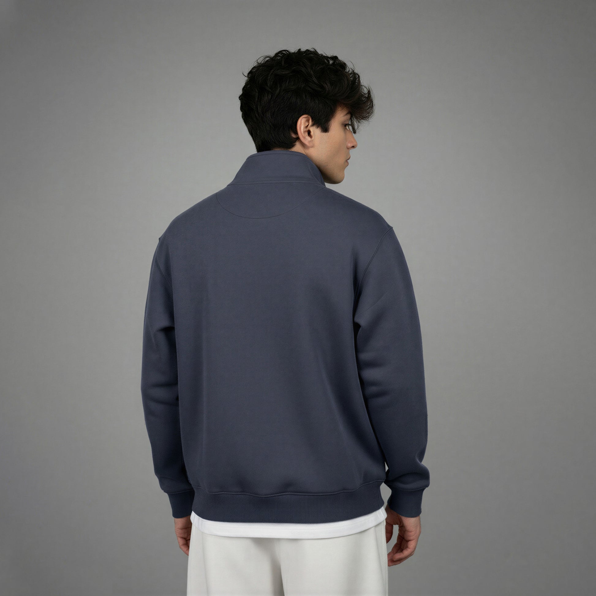 Person wearing a dark blue quarter-zip sweatshirt on a gray background