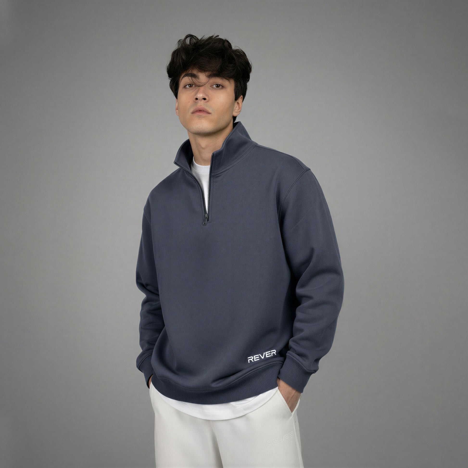 Man wearing a dark blue pullover with 'REVER' branding on a gray background