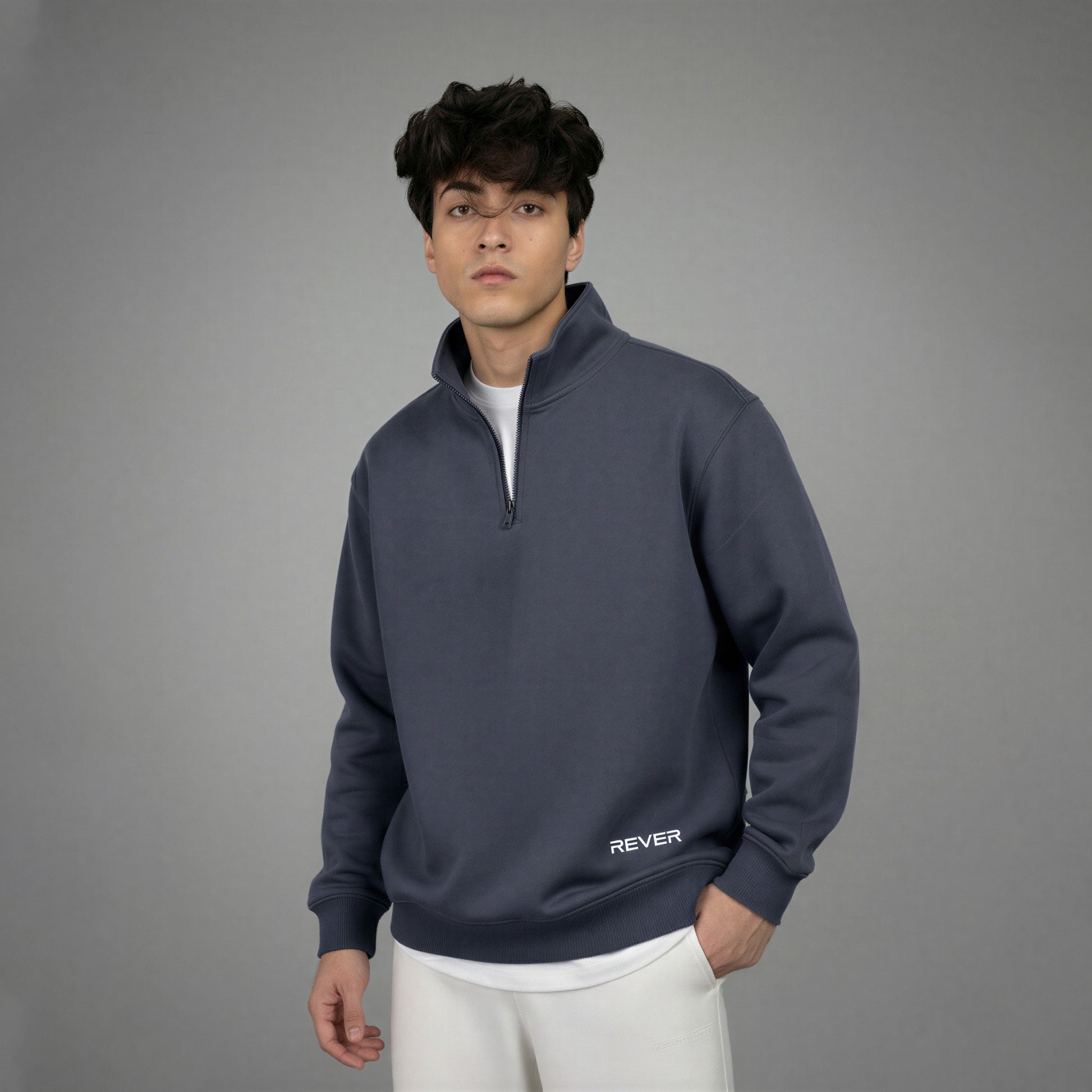Man wearing a dark blue pullover with 'REVER' branding on a gray background