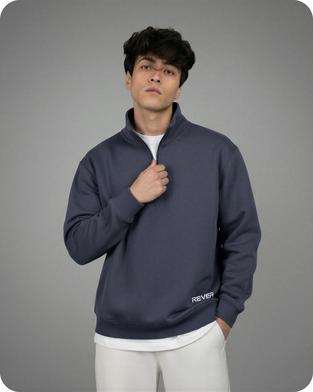 Man wearing a dark blue pullover with 'REVER' branding on a gray background