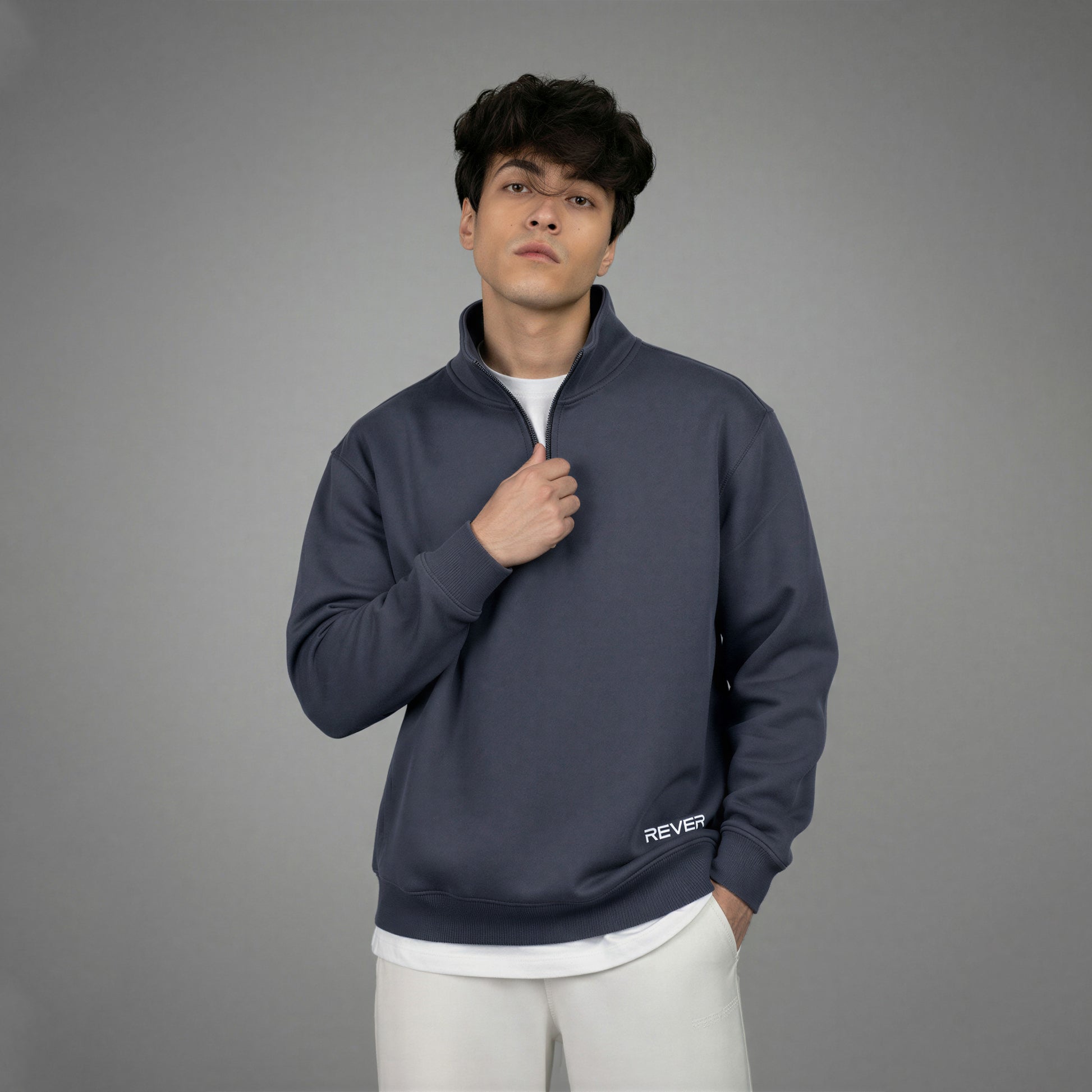 Man wearing a dark blue pullover with 'REVER' branding on a gray background