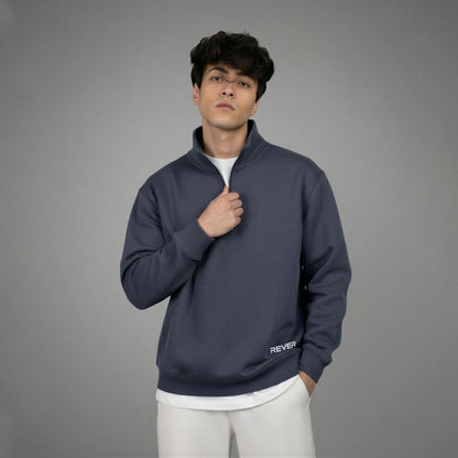 Man wearing a dark blue pullover with 'REVER' branding on a gray background