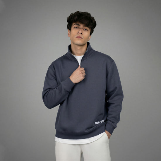 Man wearing a dark blue pullover with 'REVER' branding on a gray background