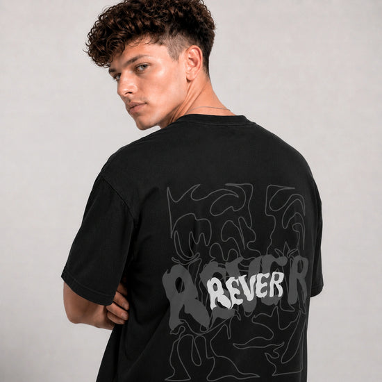 Person wearing a black t-shirt with abstract designs and 'REVER' text on the back against a plain background