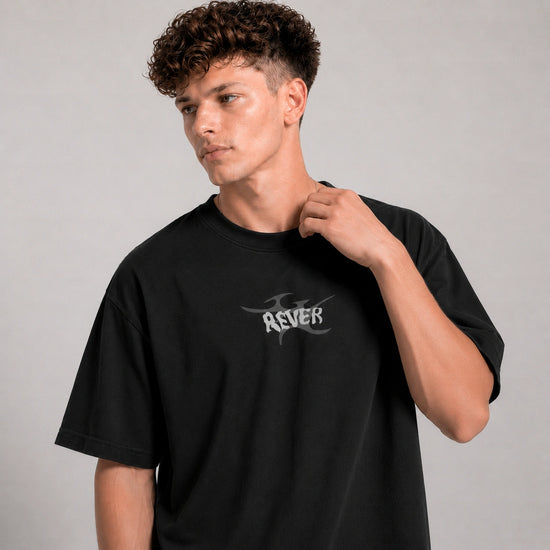 Person wearing a black t-shirt with 'REVER' logo on a gray background