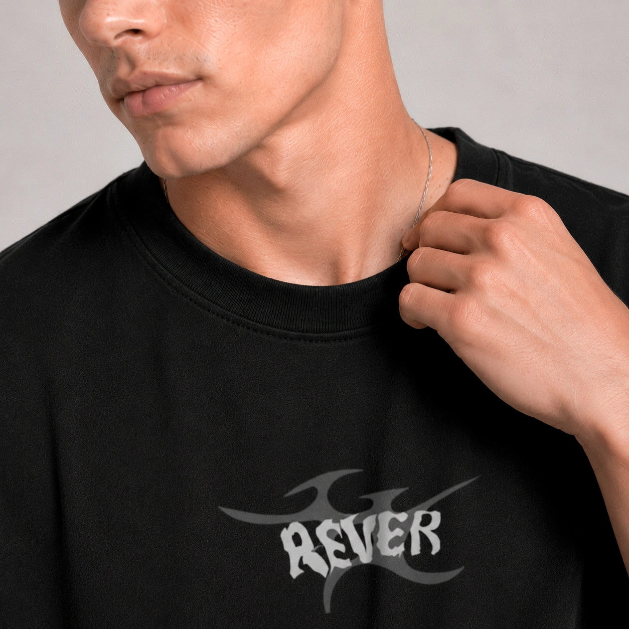 Person wearing a black t-shirt with 'REVER' logo on a plain background