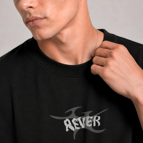 Person wearing a black t-shirt with 'REVER' logo on a plain background