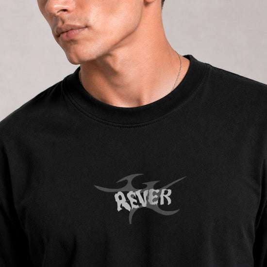 Person wearing a black t-shirt with 'REVER' logo on a plain background