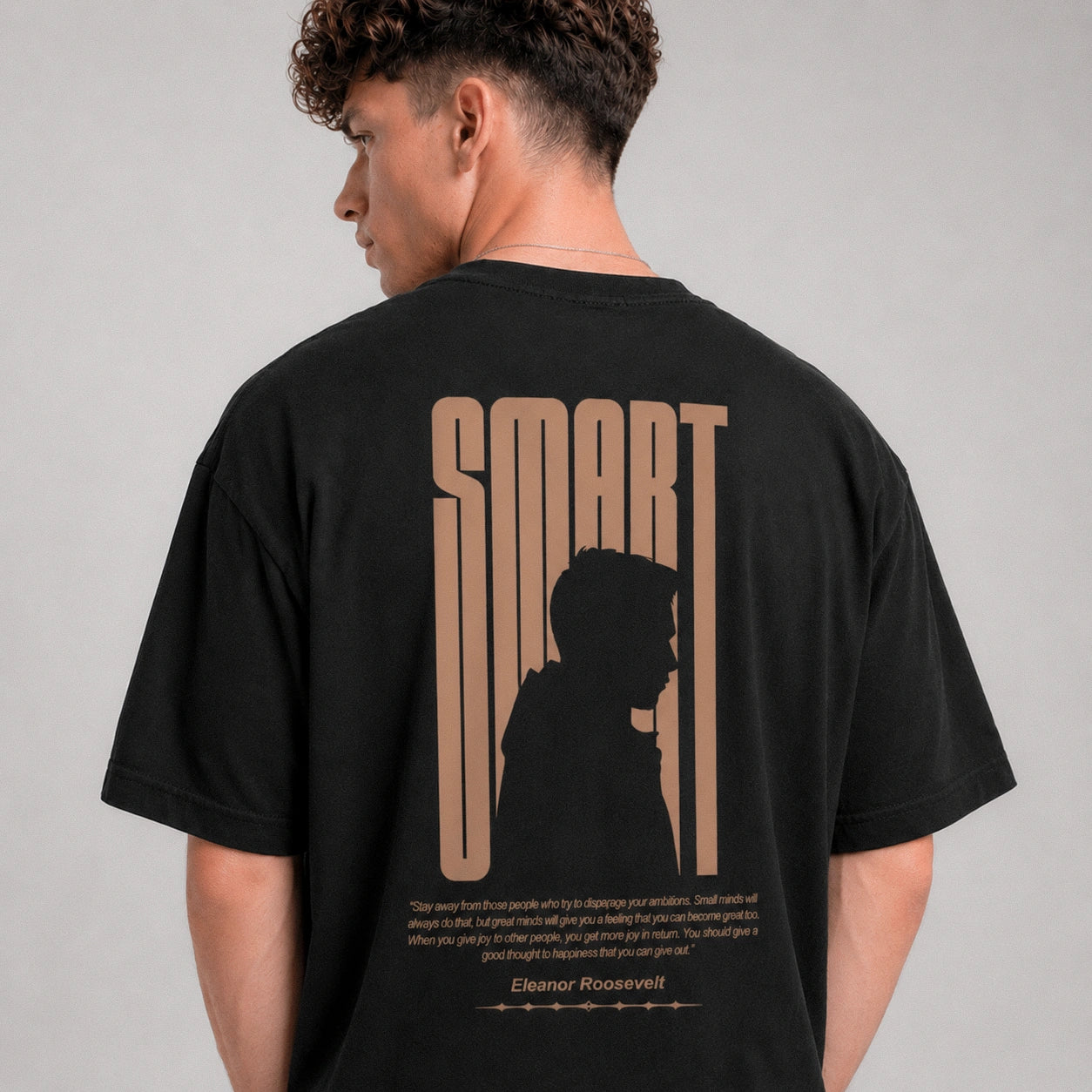 Person wearing a black t-shirt with 'SMART' design on the back, standing against a gray background.