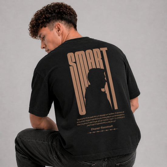 Person wearing a black t-shirt with 'SMART' design on the back, sitting against a gray background.