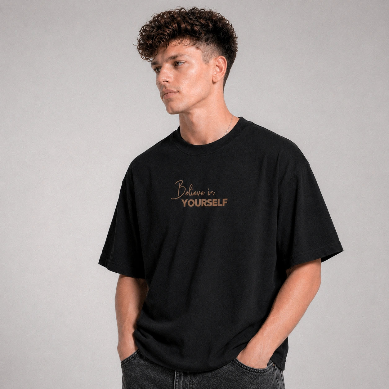Person wearing a black t-shirt with 'Believe in Yourself' text on a gray background