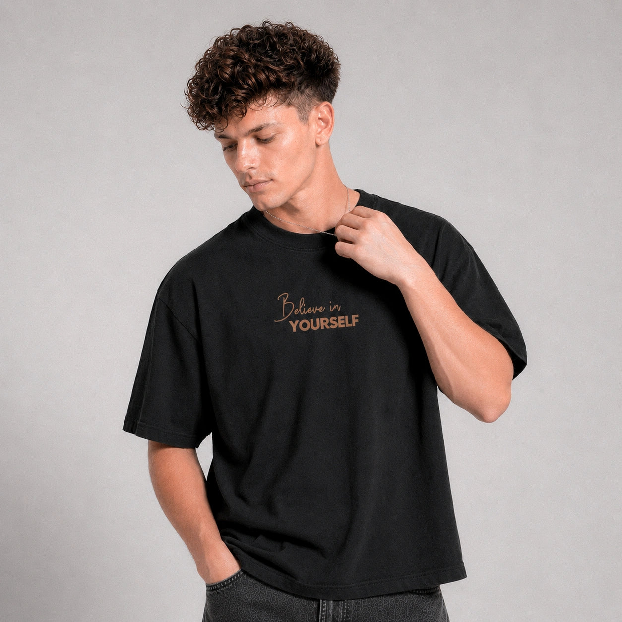 Person wearing a black t-shirt with 'Believe in Yourself' text on a gray background