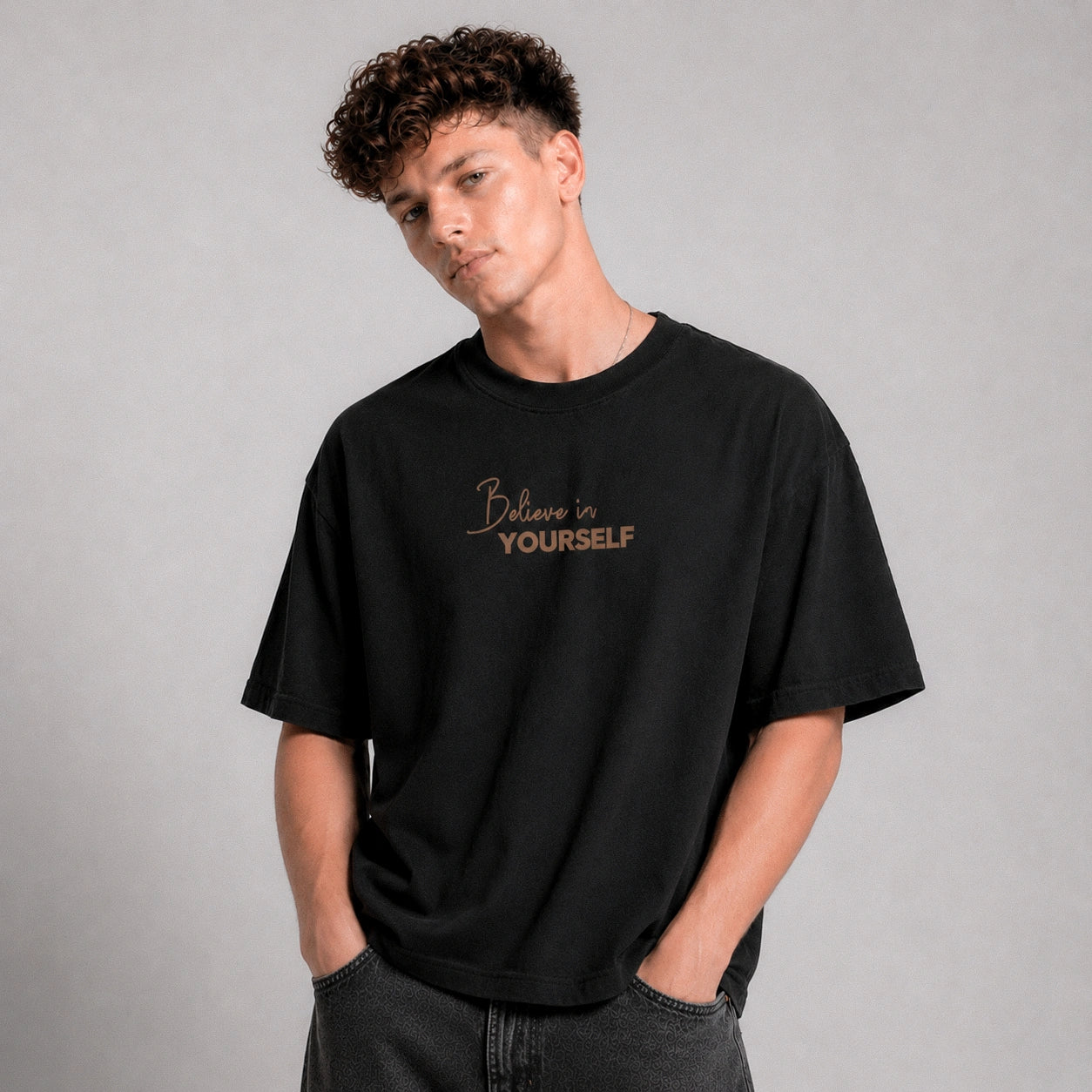 Person wearing a black t-shirt with 'Believe in Yourself' text on a gray background