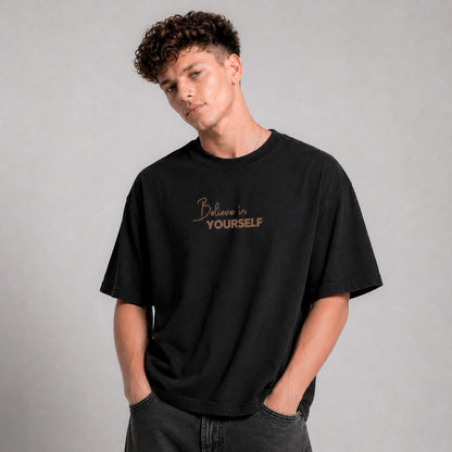 Person wearing a black t-shirt with 'Believe in Yourself' text on a gray background