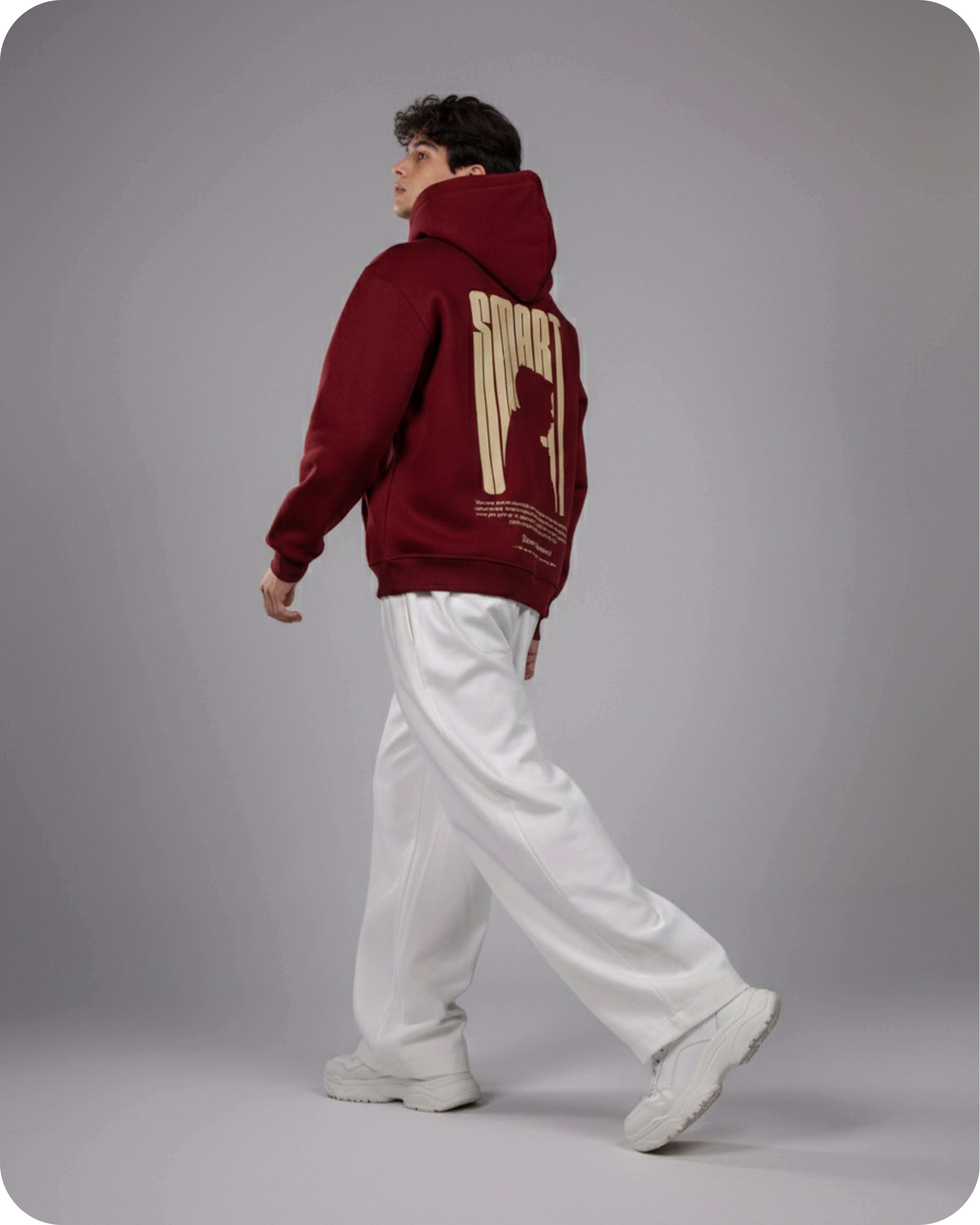 Person wearing a maroon hoodie with gold text on the back, standing against a gray background