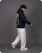 Person wearing a navy hoodie with a graphic design on the back against a gray background