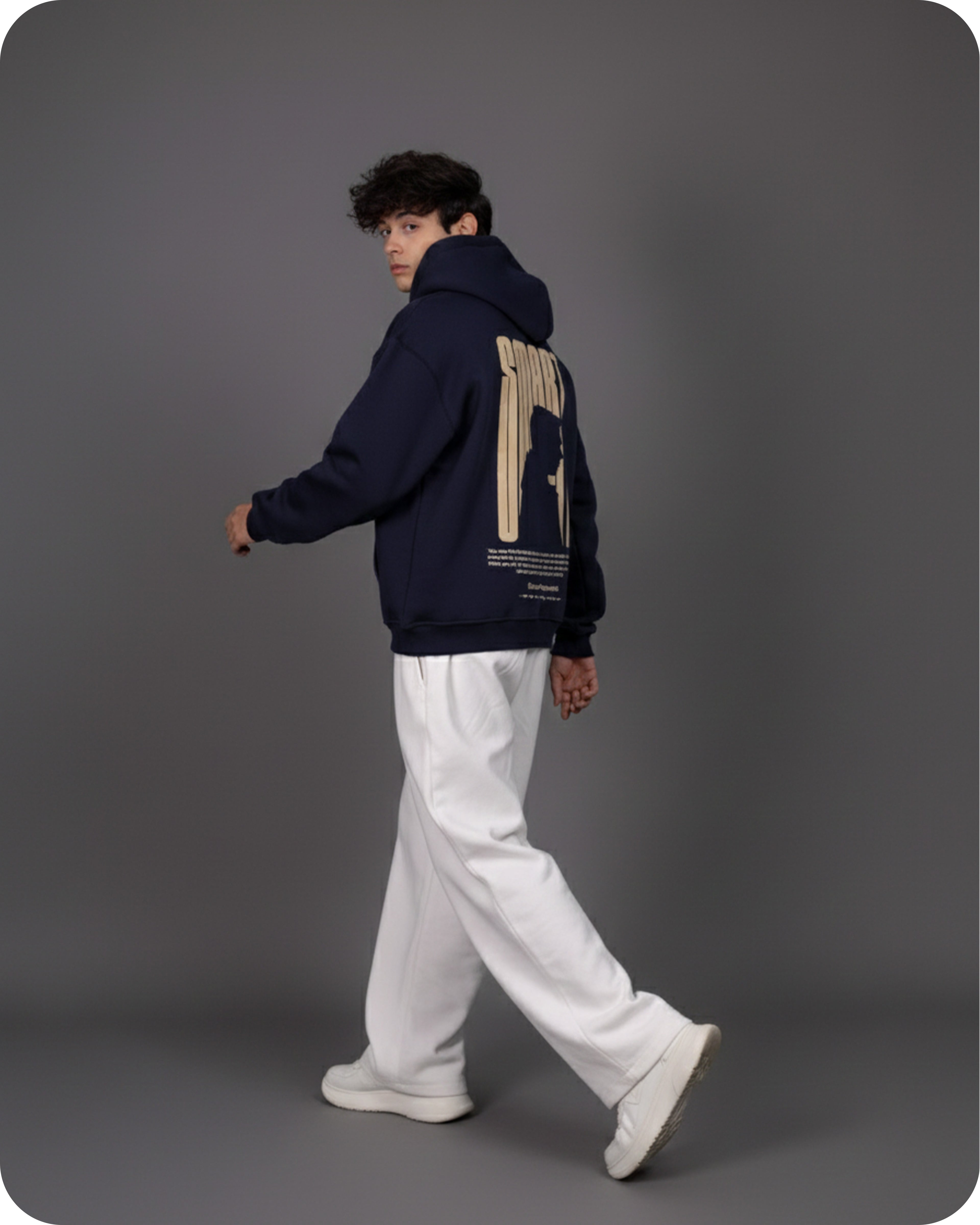 Person wearing a dark blue hoodie with a beige design on the back against a gray background