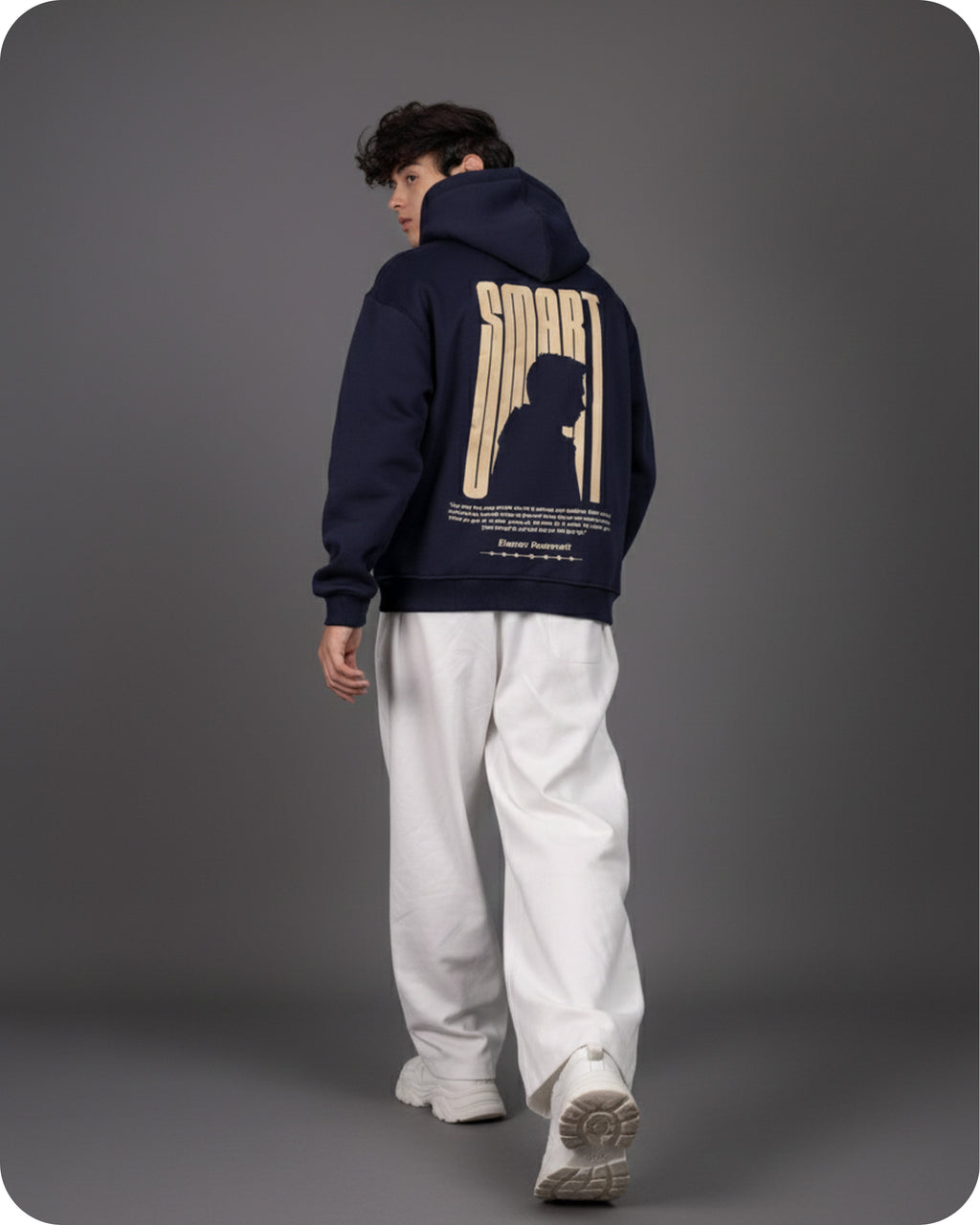 Person wearing a navy hoodie with a graphic design on the back against a gray background