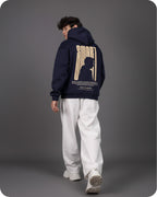 Person wearing a navy hoodie with a graphic design on the back against a gray background