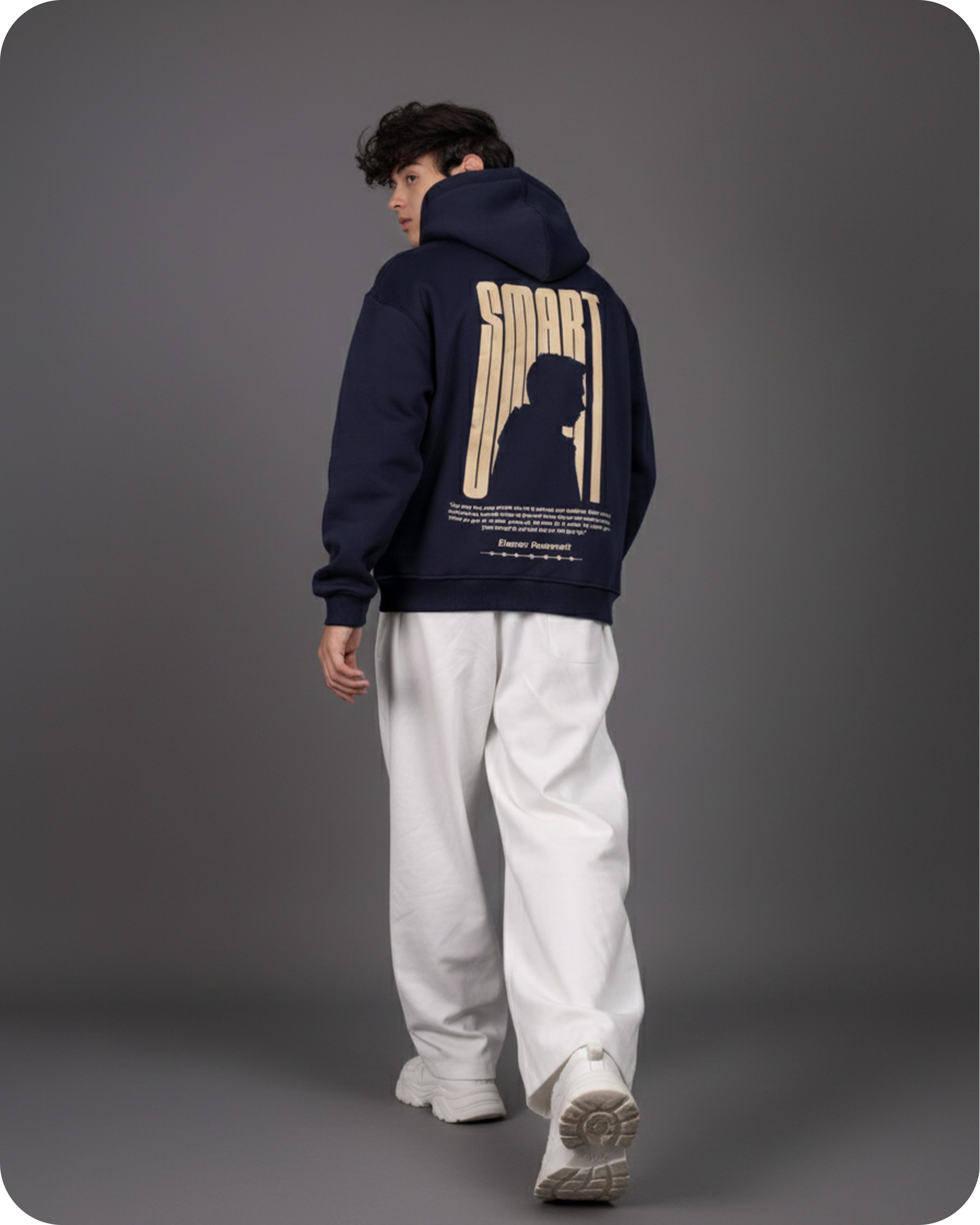 Person wearing a navy hoodie with a graphic design on the back against a gray background