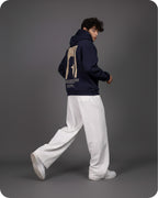 Person wearing a navy hoodie with a graphic design on the back, walking against a gray background