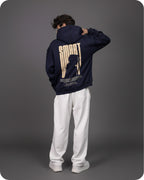 Person wearing a navy hoodie with a graphic design on the back against a gray background