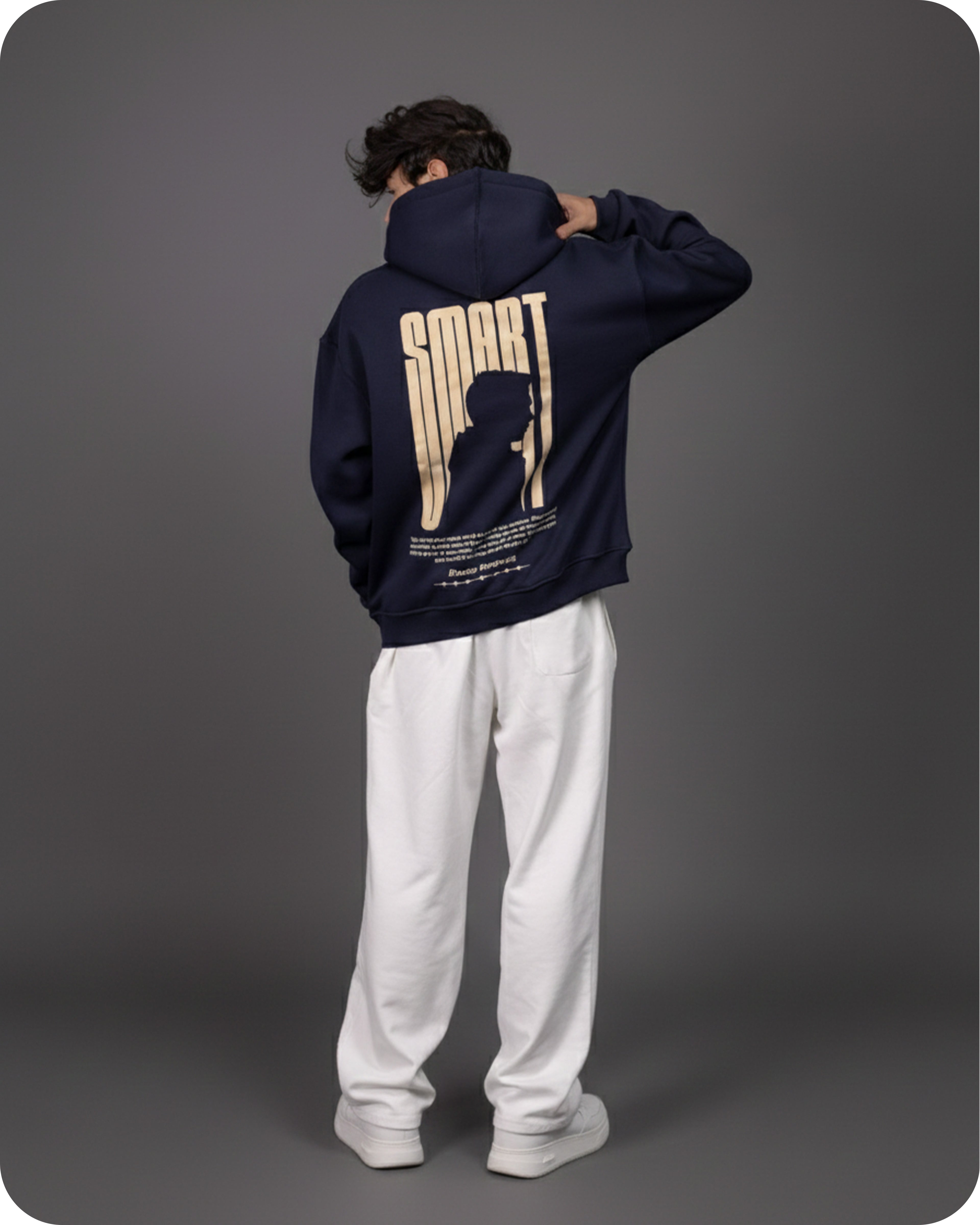 Person wearing a navy hoodie with a graphic design on the back against a gray background