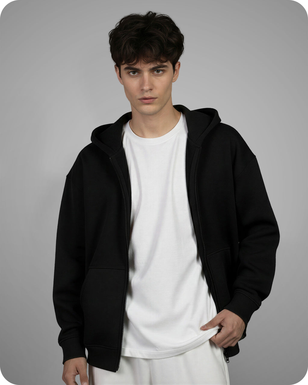 Person wearing a black hoodie over a white shirt on a gray background