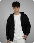 Person wearing a black hoodie over a white shirt on a gray background