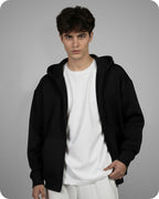 Person wearing a black hoodie over a white shirt on a gray background