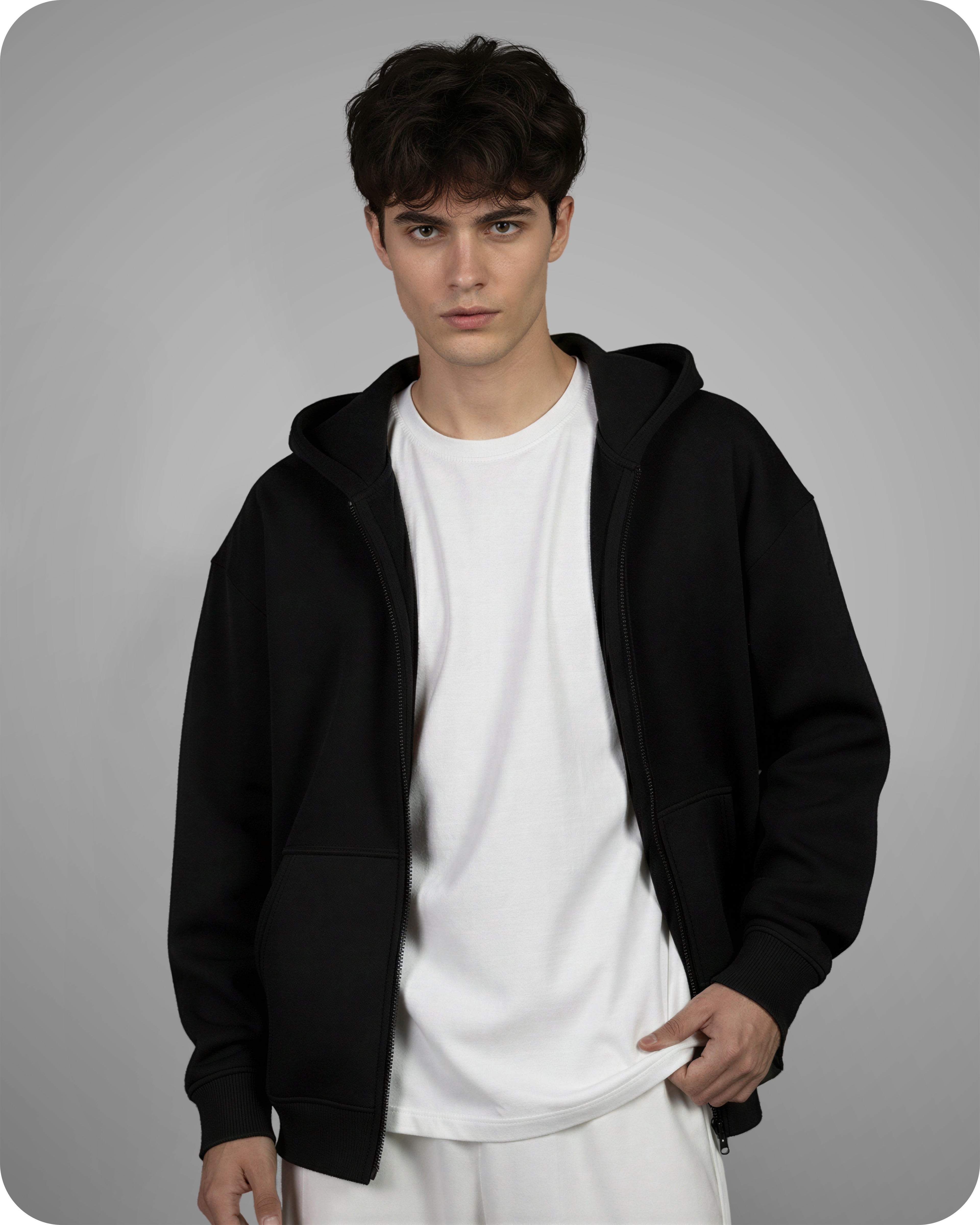 Person wearing a black hoodie over a white shirt on a gray background