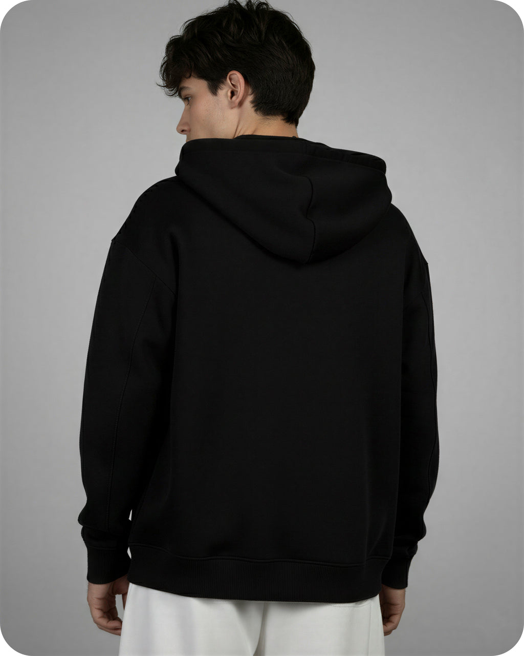 Person wearing a black hoodie from behind on a gray background