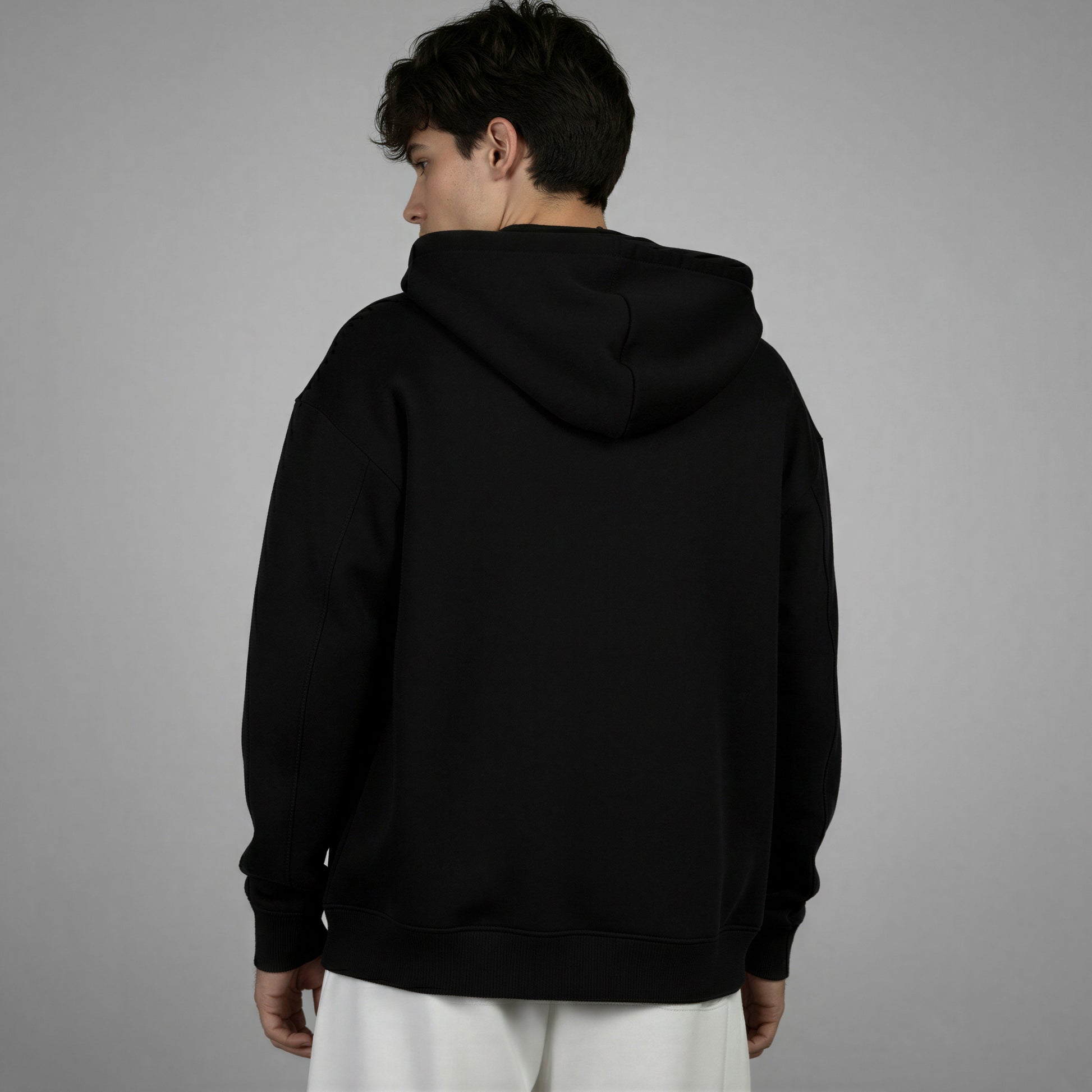 Person wearing a black hoodie from behind on a gray background